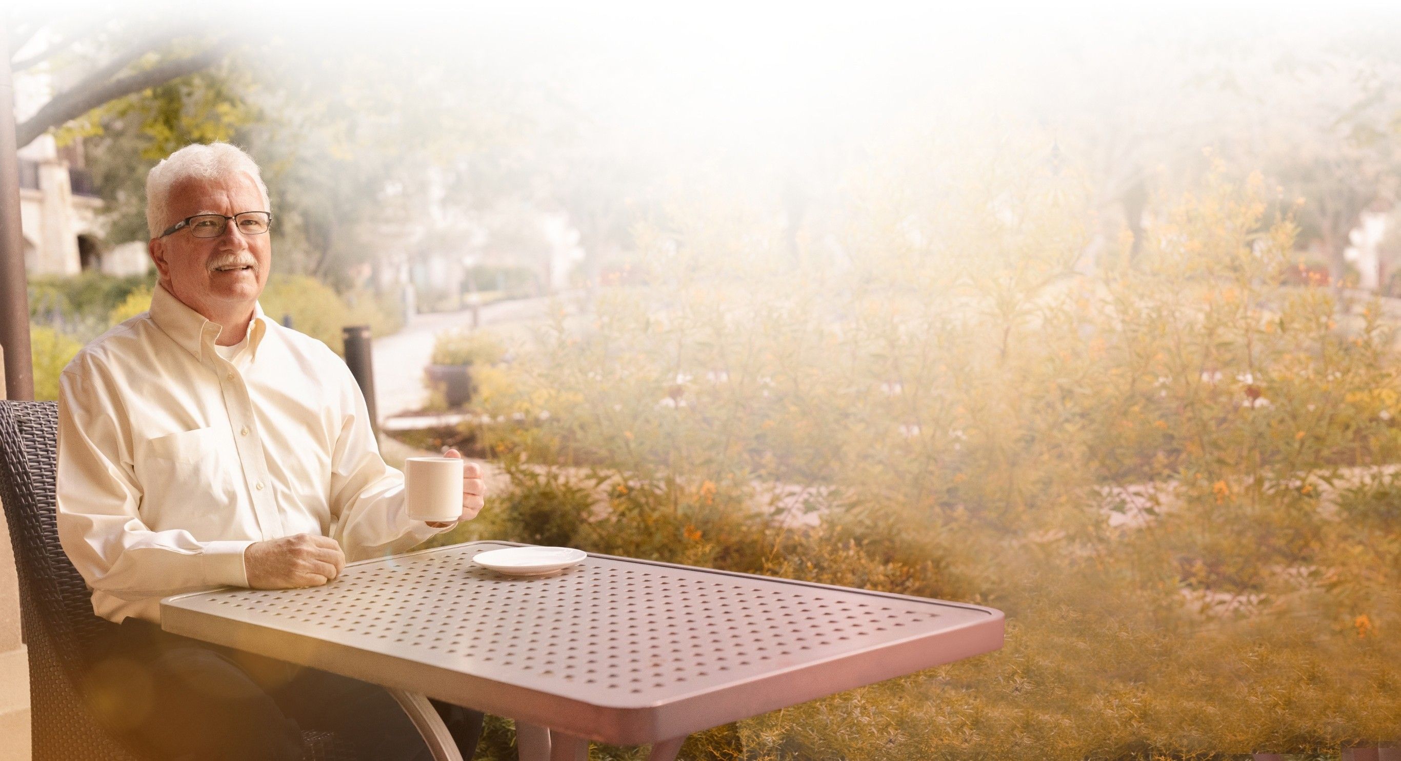 Gary, treated with AMVUTTRA® (vutrisiran), sitting at a table in a park on a sunny day.